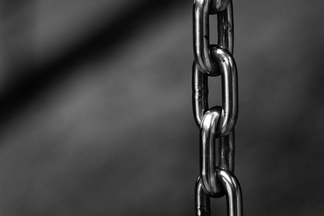 Detailed close-up of a strong shiny metallic chain link against a blurred background, emphasizing security.